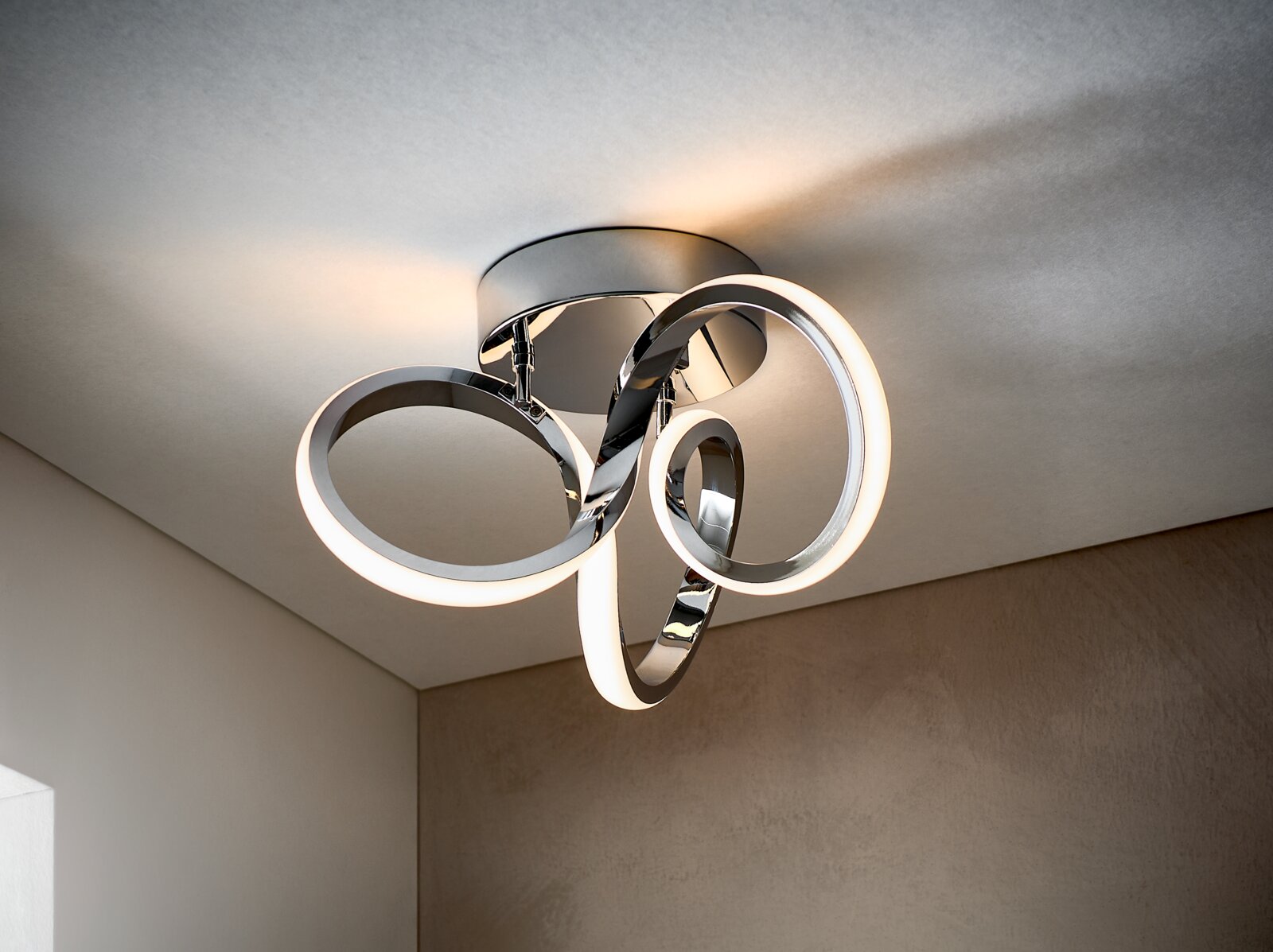 Moderne LED-Deckenleuchte mit drei leuchtenden Ring-Elementen in Chromoptik, warmweißes Licht, Ansicht schräg von unten an der Decke montiert