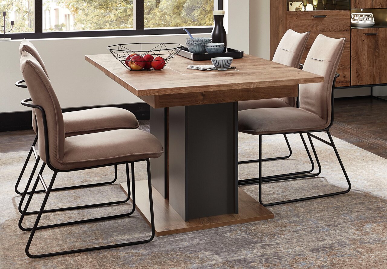 Moderne houten eettafel met metalen onderstel, omringd door gestoffeerde stoelen, zijaanzicht