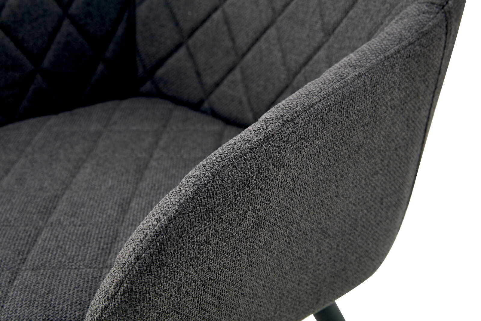 Nahaufnahme eines dunkelgrauen, gepolsterten Stoffstuhls mit gesteppter Rückenlehne und Armlehne, schräg von vorne/rechts fotografiert