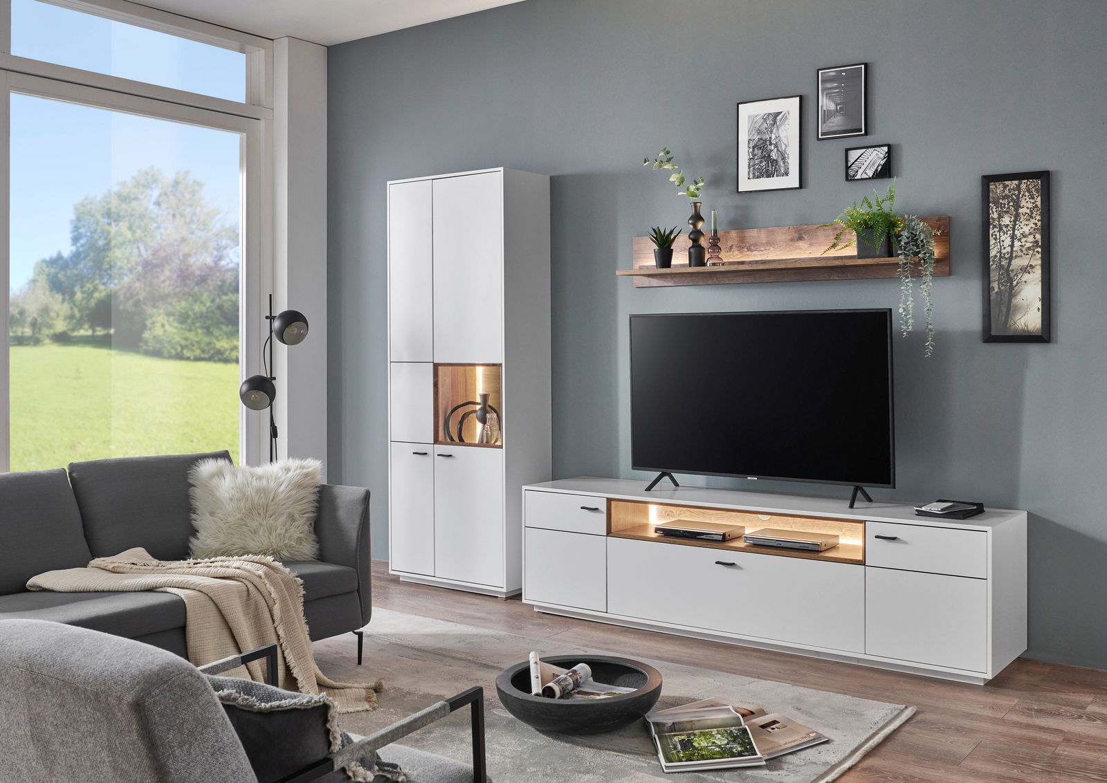 Moderne Wohnzimmer-Wandkombination in Weiß mit TV-Schrank, Vitrine und Wandregal, seitliche Perspektive.