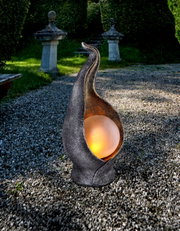 De Oliver-zonnelamp in een tuin, gezien van voren, met een verlichte bol in een kunstig gebogen metalen omhulsel.