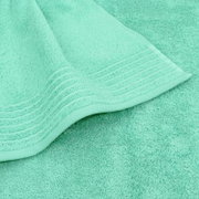 Close-up van een mintgroene badstofhanddoek met rand, schuin van bovenaf gefotografeerd