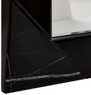 Nahaufnahme eines Spiegels mit schwarzem, geometrischem Rahmen und Marmoroptik, perspektivisch von der Seite aufgenommen.