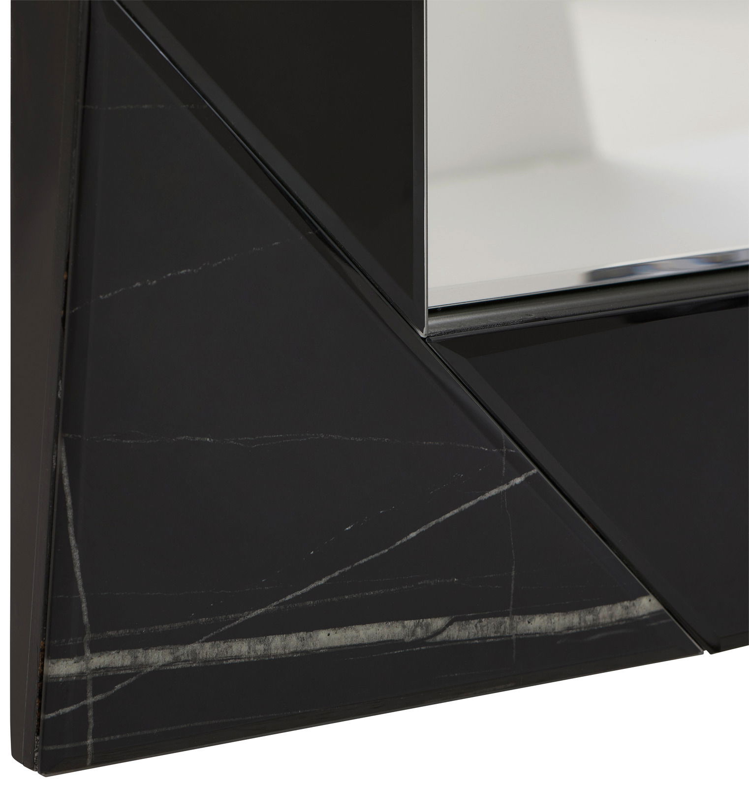 Nahaufnahme eines Spiegels mit schwarzem, geometrischem Rahmen und Marmoroptik, perspektivisch von der Seite aufgenommen.