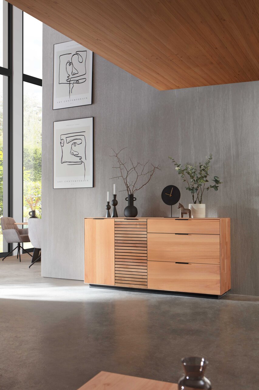 Modernes Sideboard aus Holz mit Schubladen und Lamellentür, seitliche Perspektive, dekoriert mit Vasen und Uhr.