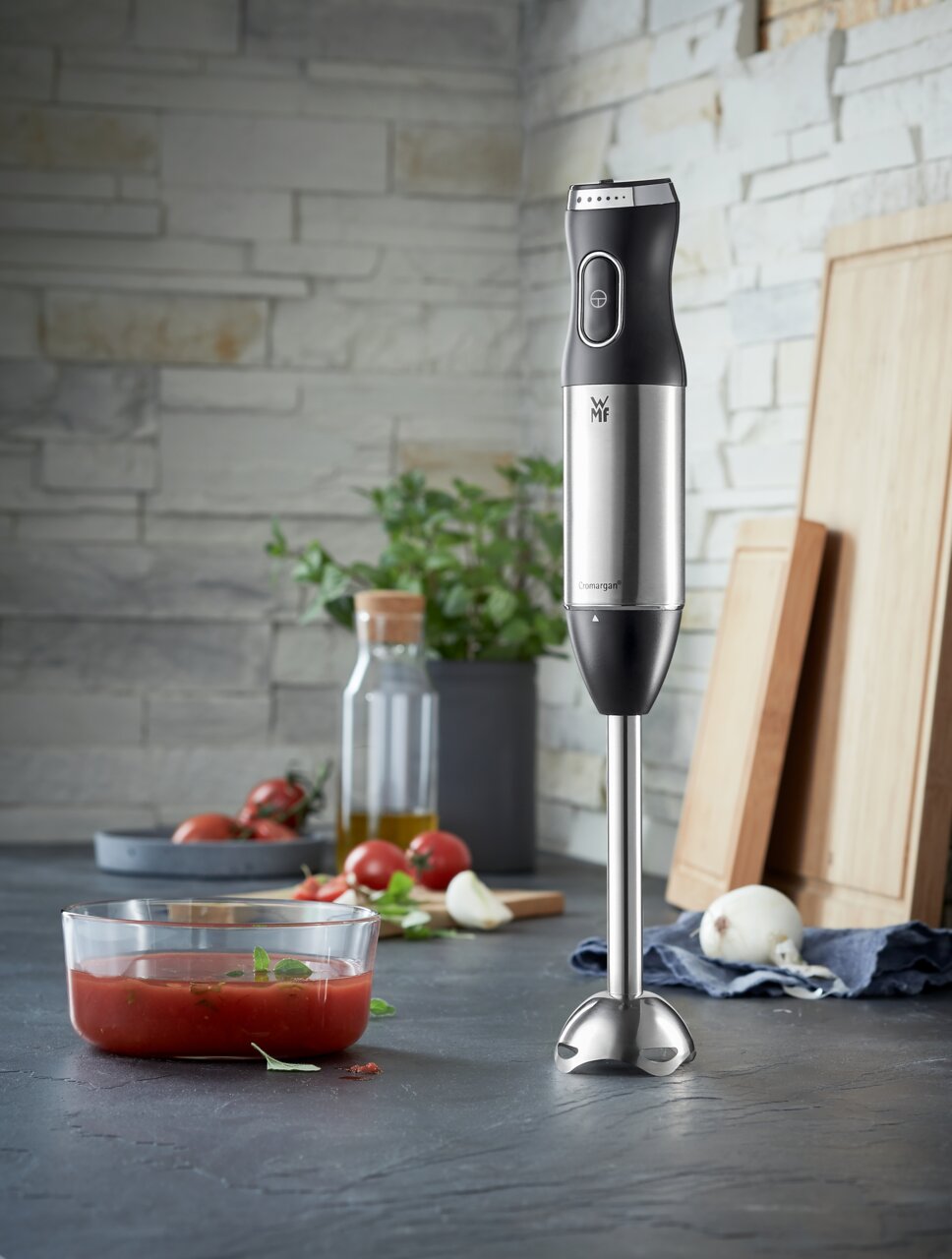 Stabmixer Kult-X in einer modernen Küche, frontal abgebildet neben frischen Zutaten wie Tomaten und Zwiebeln.