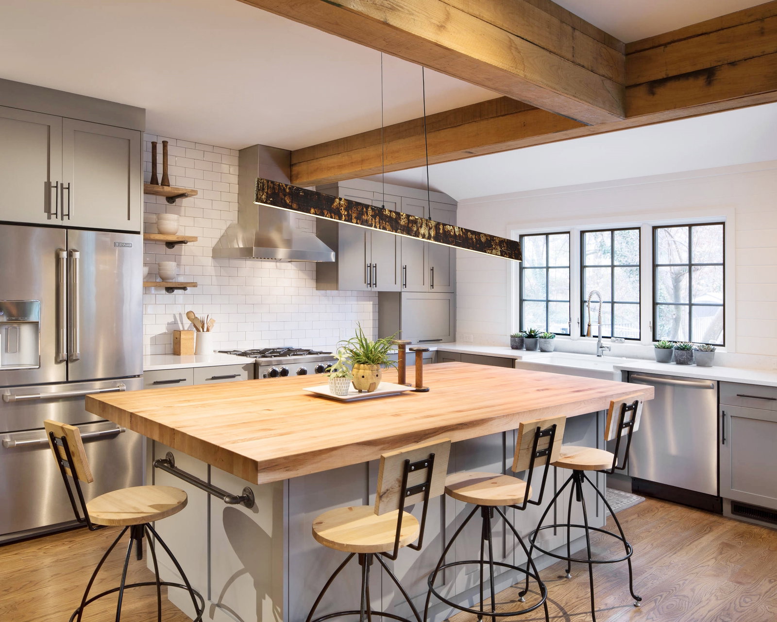 Moderne LED-Hängeleuchte über einem Kücheninsel aus Holz, seitliche Perspektive.