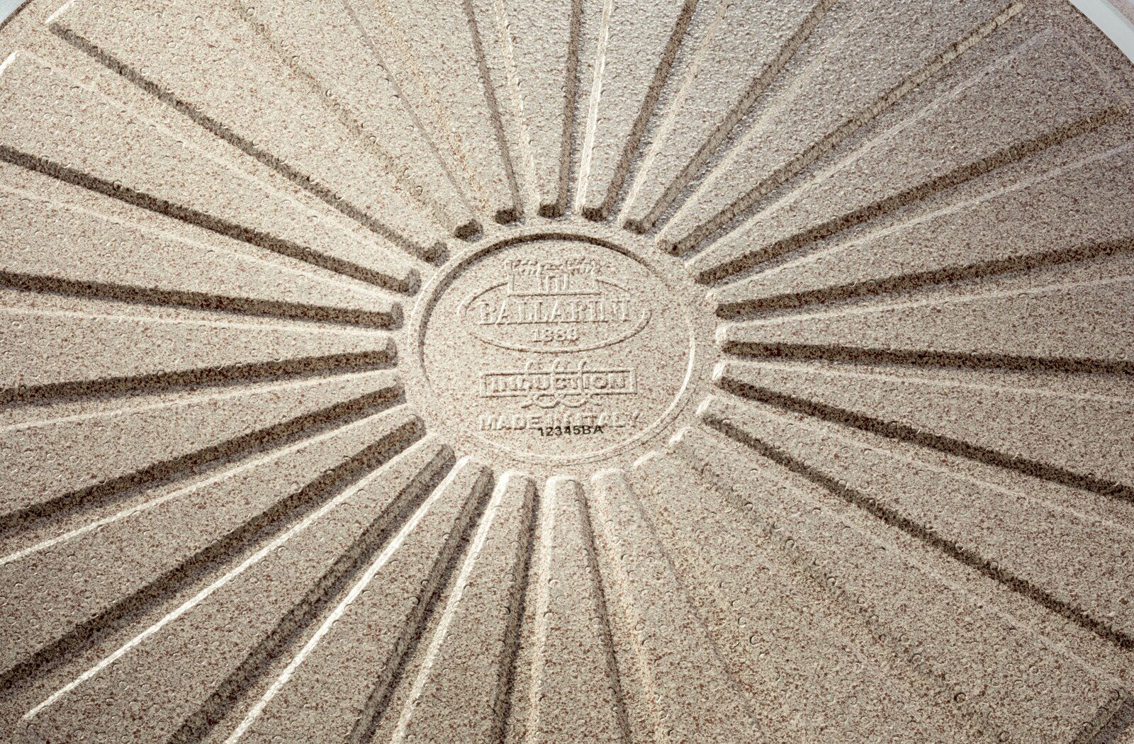 Nahaufnahme der Unterseite einer Bratpfanne mit radialem Muster und Prägung in der Mitte.