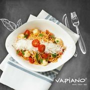 Vogelperspektive auf einen Teller Spaghetti mit Tomaten, Mozzarella und geriebenem Käse, serviert auf einer Serviette mit Vapiano-Logo.