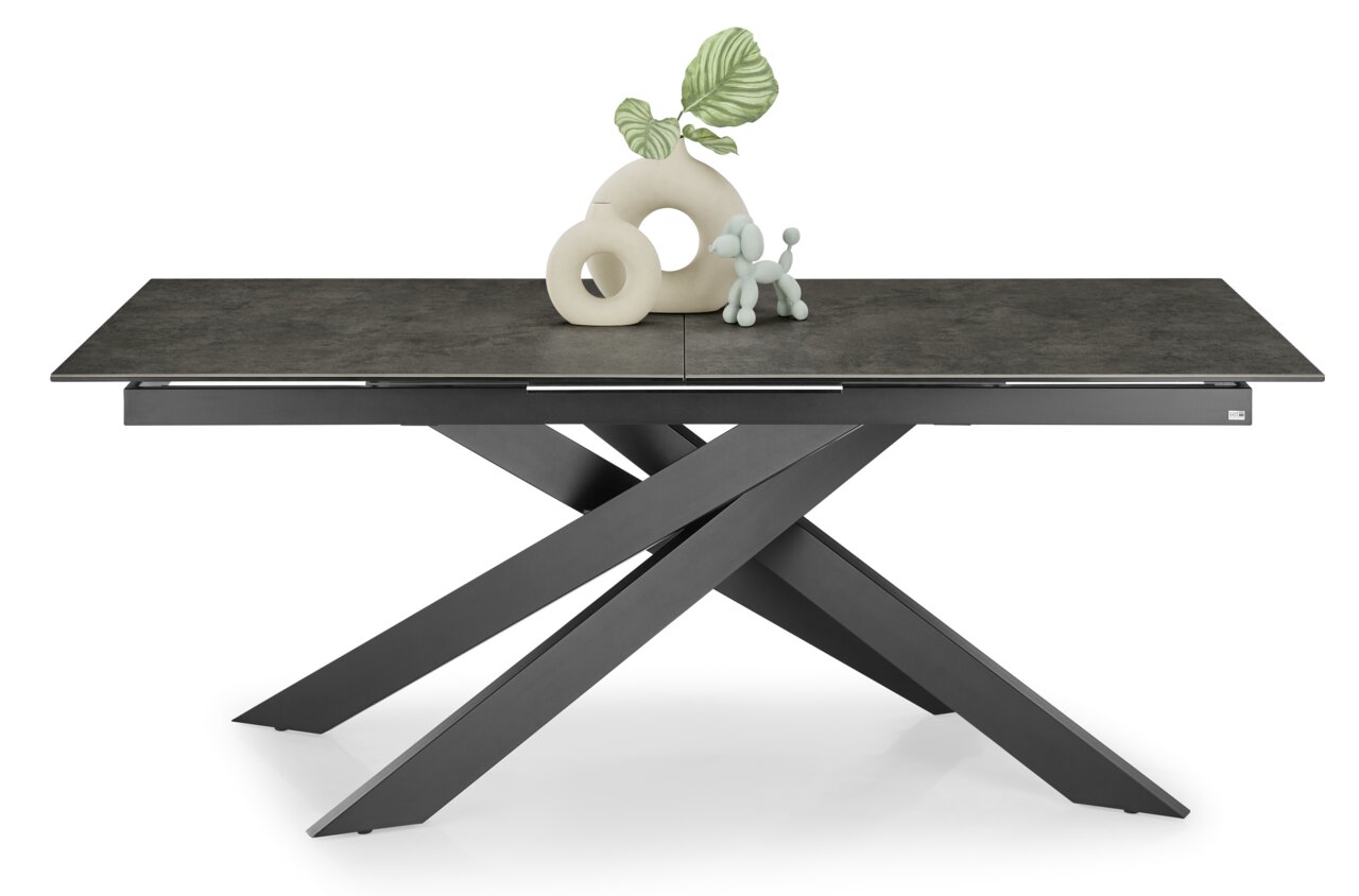 Moderne eettafel met donker tafelblad en sculpturaal, gekruist onderstel, gezien vanaf de voorkant.