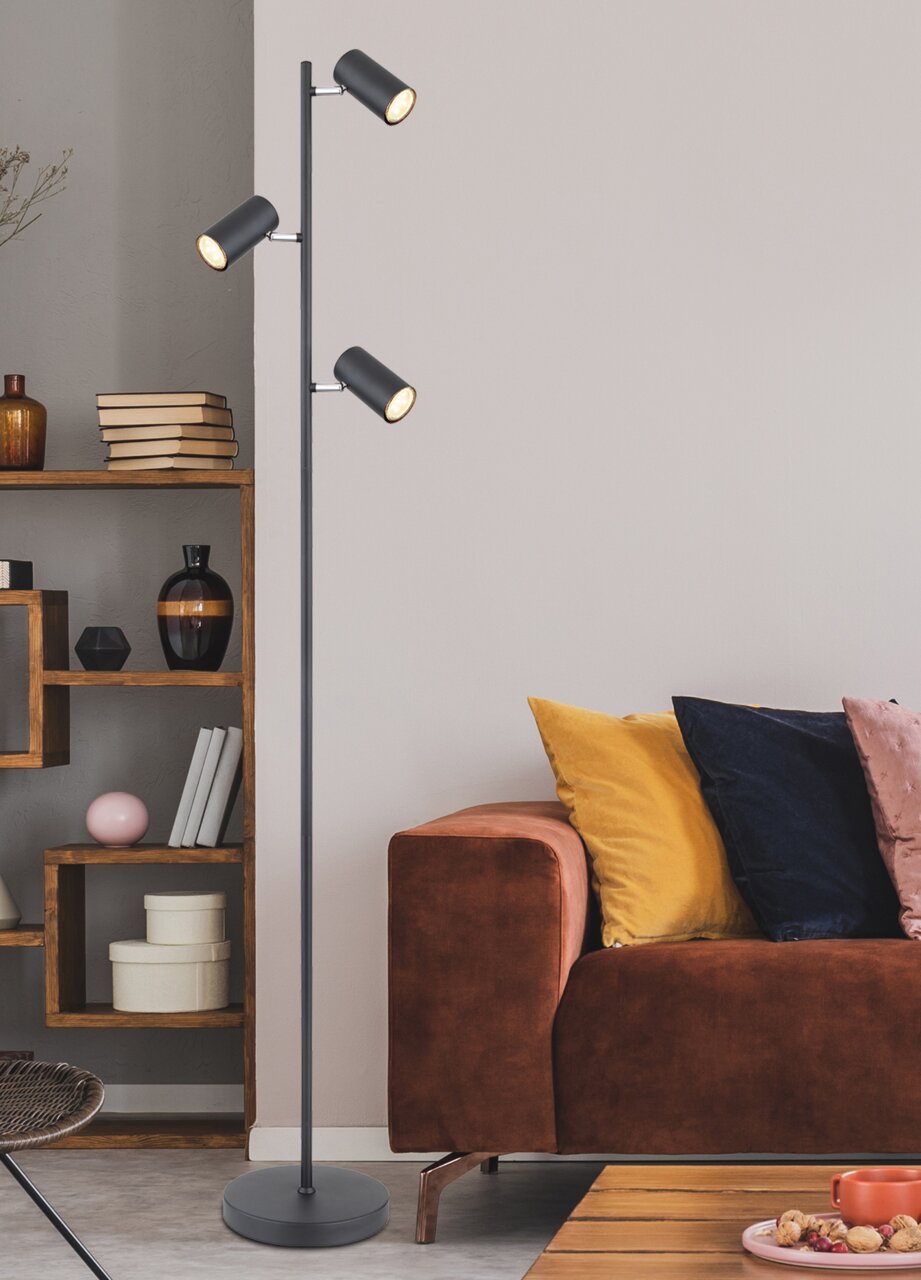 Moderne Stehleuchte mit drei verstellbaren Leuchten in einem gemütlichen Wohnzimmer, seitliche Perspektive