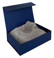 Geschenkset in einer offenen blauen Box mit weicher, grauer Decke, Ansicht von oben.