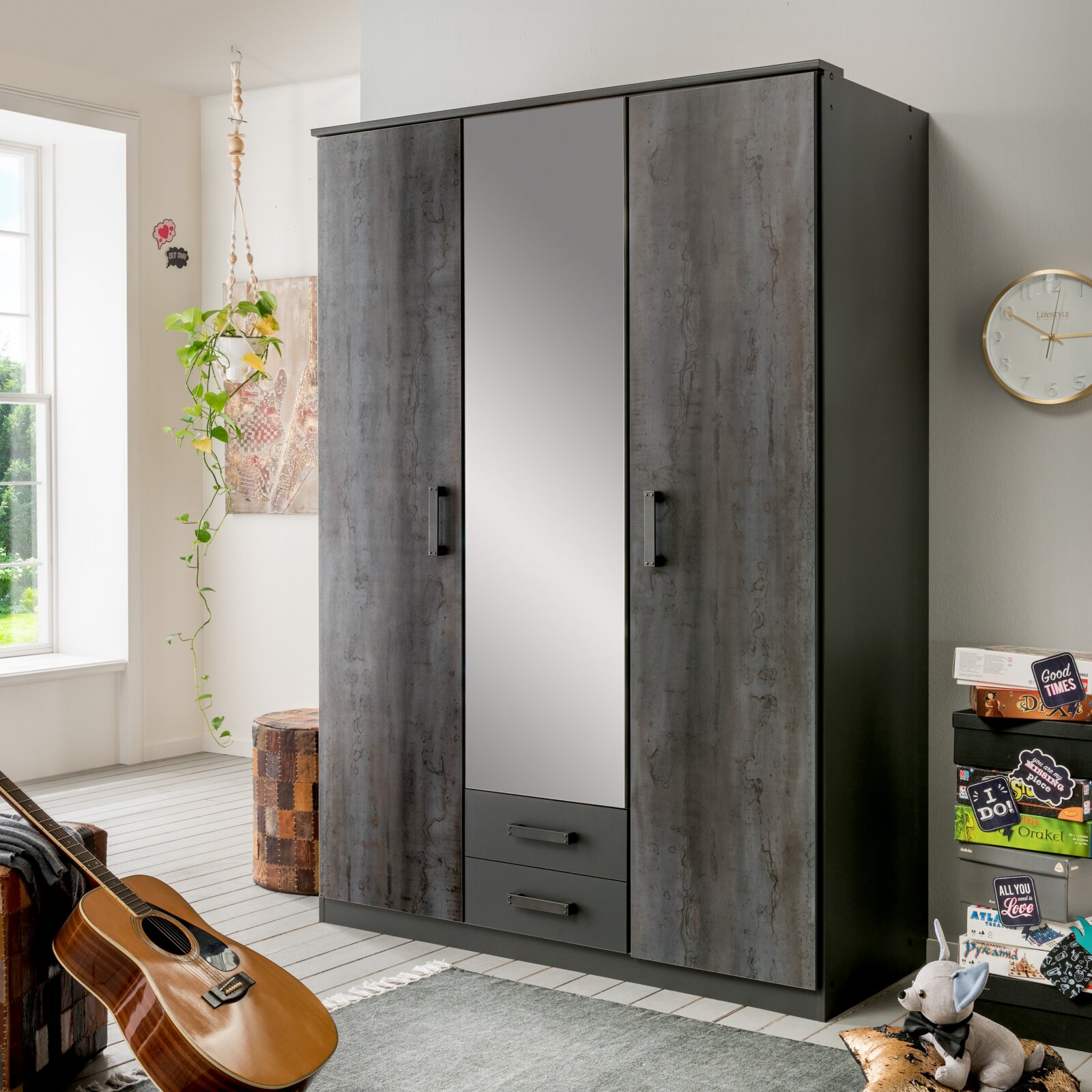 Drehtürenschrank mit drei Türen, mittlere Tür mit Spiegel, in einem modernen Raum mit Gitarre und Dekorationen, seitliche Perspektive