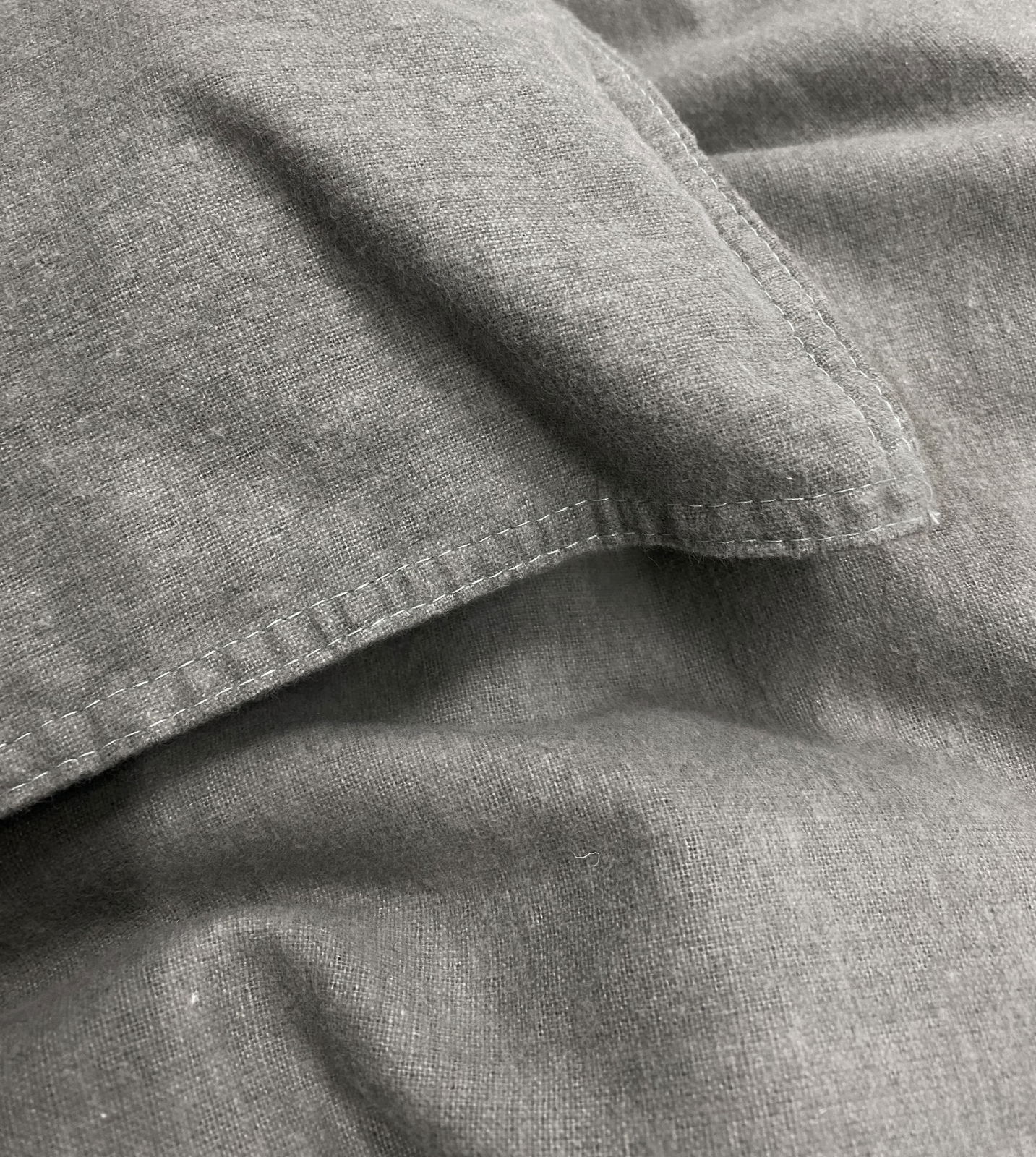 Nahaufnahme von grauer Bettwäsche mit sichtbaren Nähten und Textur