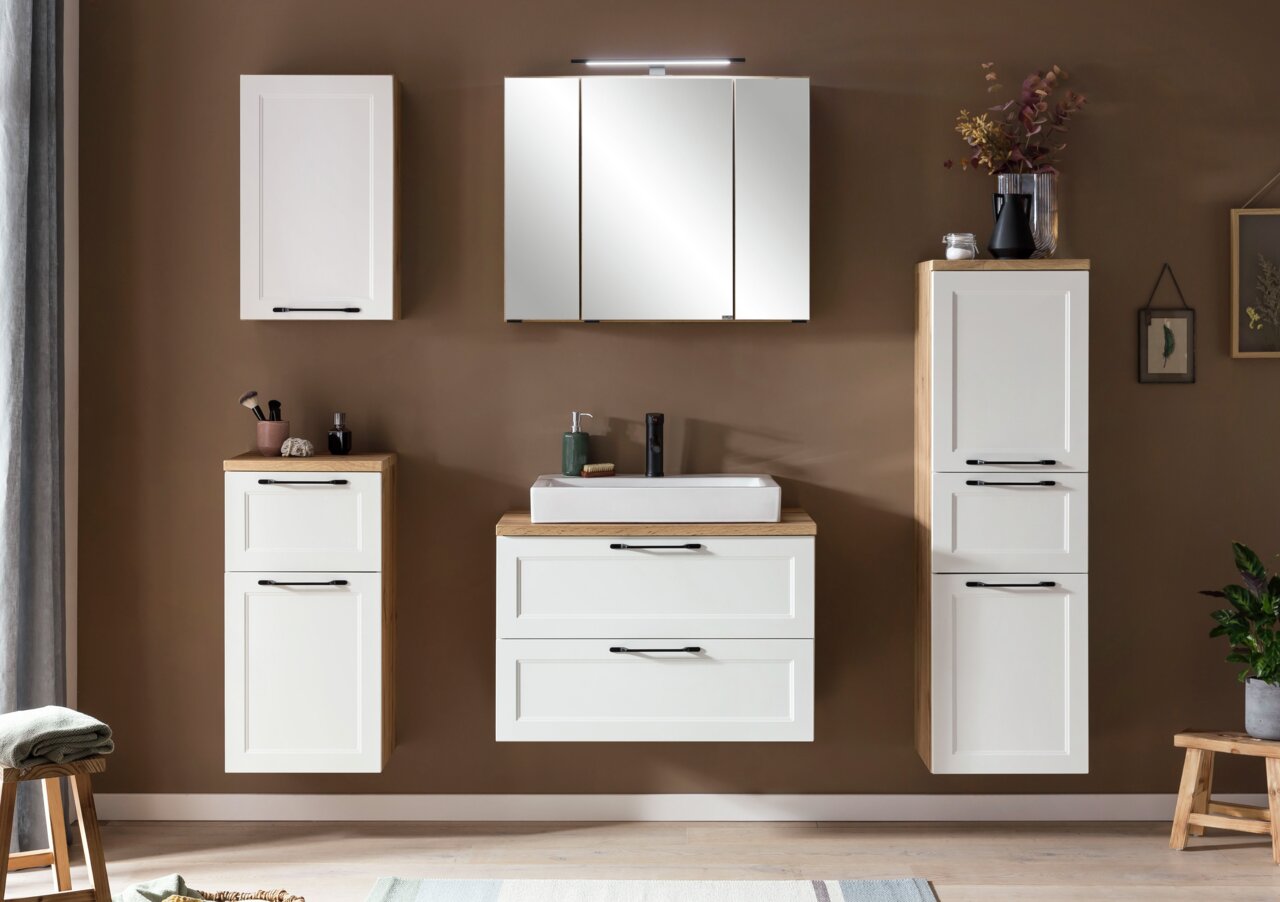 Moderne Badezimmermöbel in Weiß mit Holzdetails, bestehend aus einem Midischrank, einem Waschbeckenunterschrank und einem Spiegelschrank, frontal betrachtet.