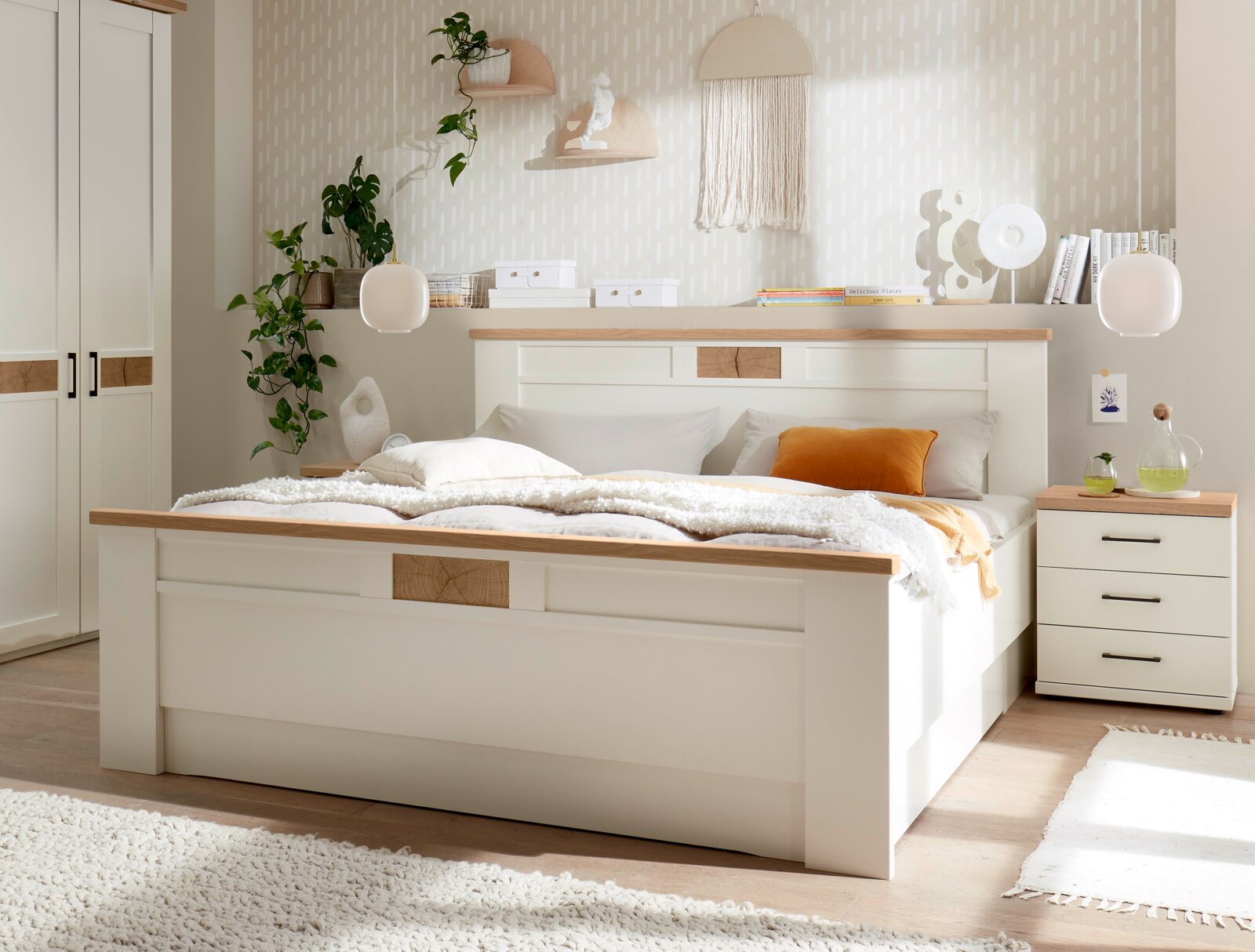 Modernes weißes Holzbett mit Eiche-Akzenten und gepolsterter Bettwäsche in hellem Schlafzimmer, aufgenommen in frontaler Perspektive mit leichtem Blick von links.