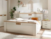 Modernes weißes Holzbett mit Eiche-Akzenten und gepolsterter Bettwäsche in hellem Schlafzimmer, aufgenommen in frontaler Perspektive mit leichtem Blick von links.