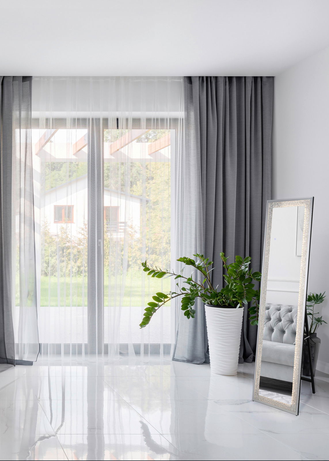 LED-Standspiegel 40x160cm in einem modernen Raum, schräg an eine Wand gelehnt, mit einem großen Fenster und einem Pflanzenarrangement im Hintergrund.