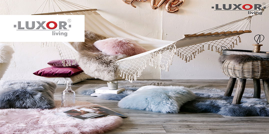 Eine Hängematte mit weichen Fellkissen und Fellteppichen in Pastelltönen. Logo Luxor living