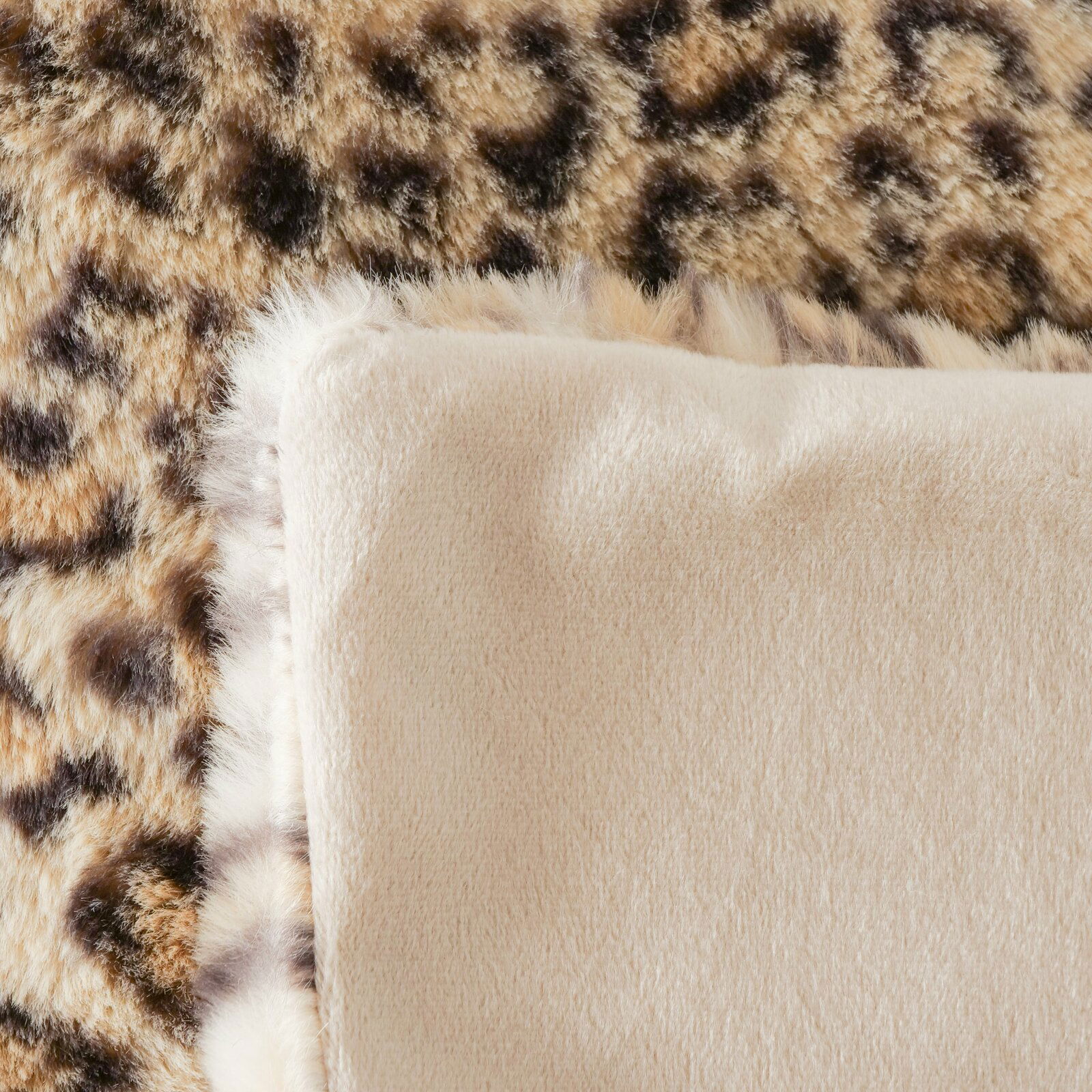 Nahaufnahme einer Decke mit Leopardenmuster und weicher, beiger Rückseite.