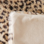 Nahaufnahme einer Decke mit Leopardenmuster und weicher, beiger Rückseite.