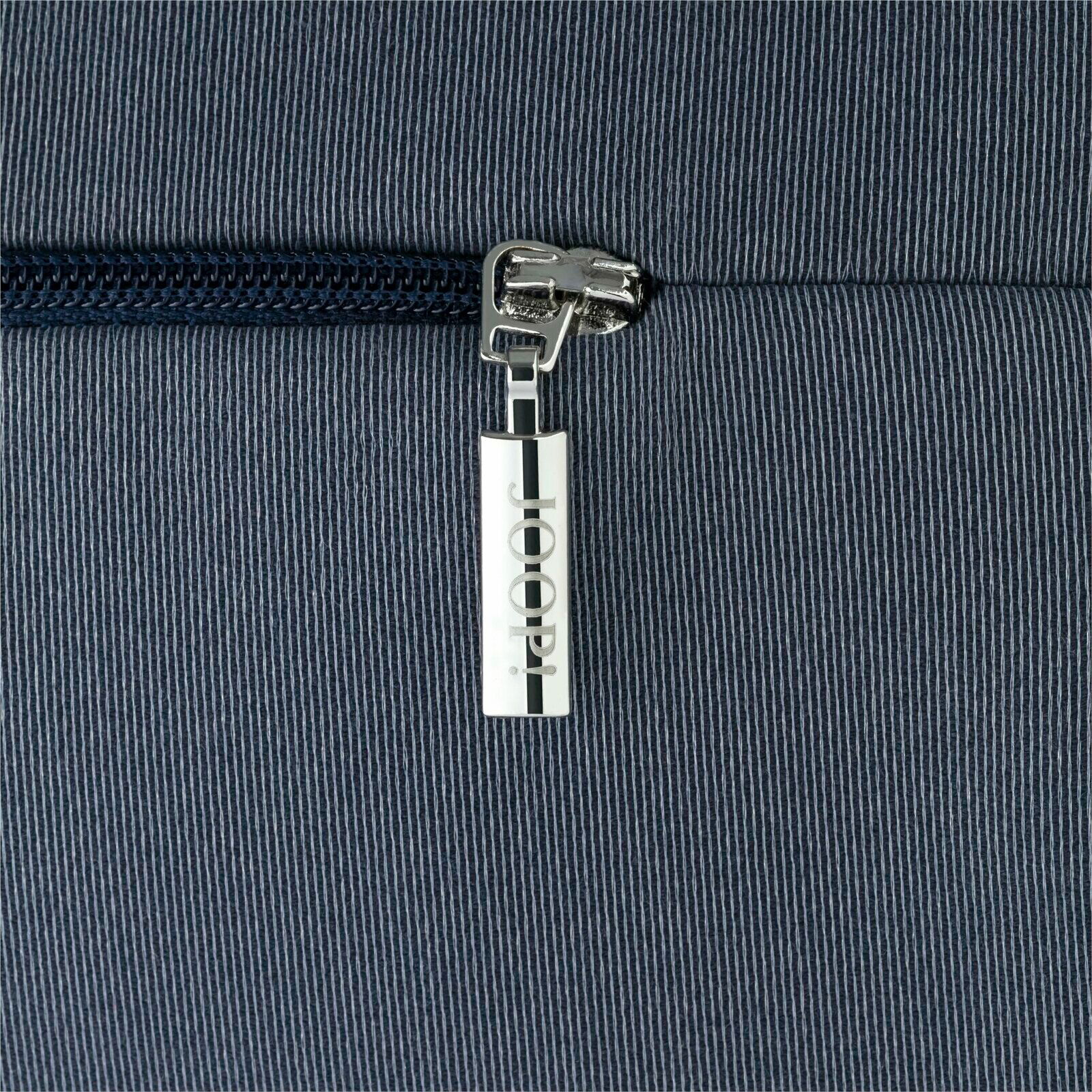 Nahaufnahme eines Reißverschlusses mit einem Anhänger, der die Aufschrift 'JOOP!' trägt, auf einem gestreiften Stoff.