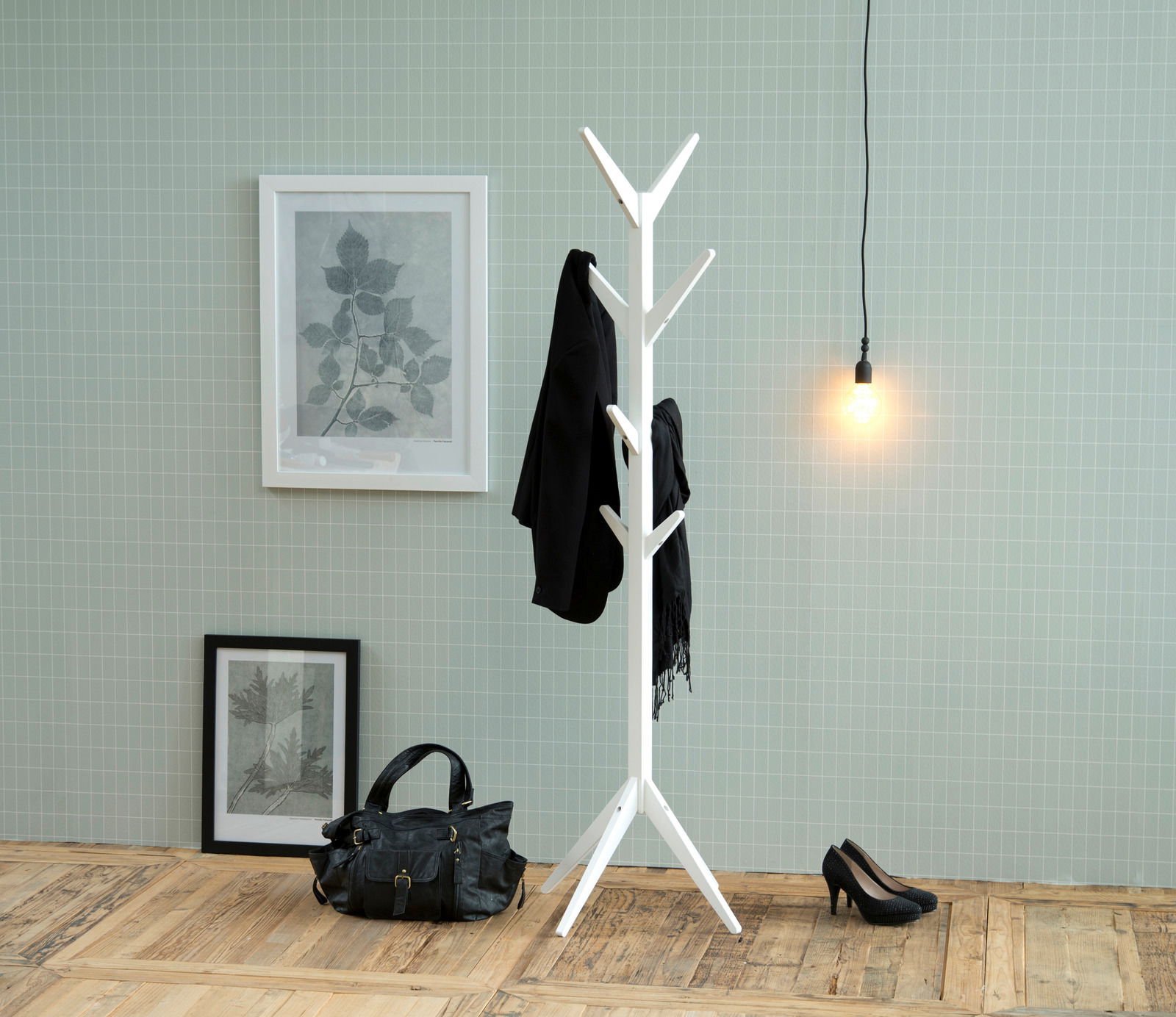 Weißer Garderobenständer mit mehreren Haken, frontal fotografiert, in einem stilvoll eingerichteten Raum mit Holzboden, Wandbildern und einer Hängelampe.