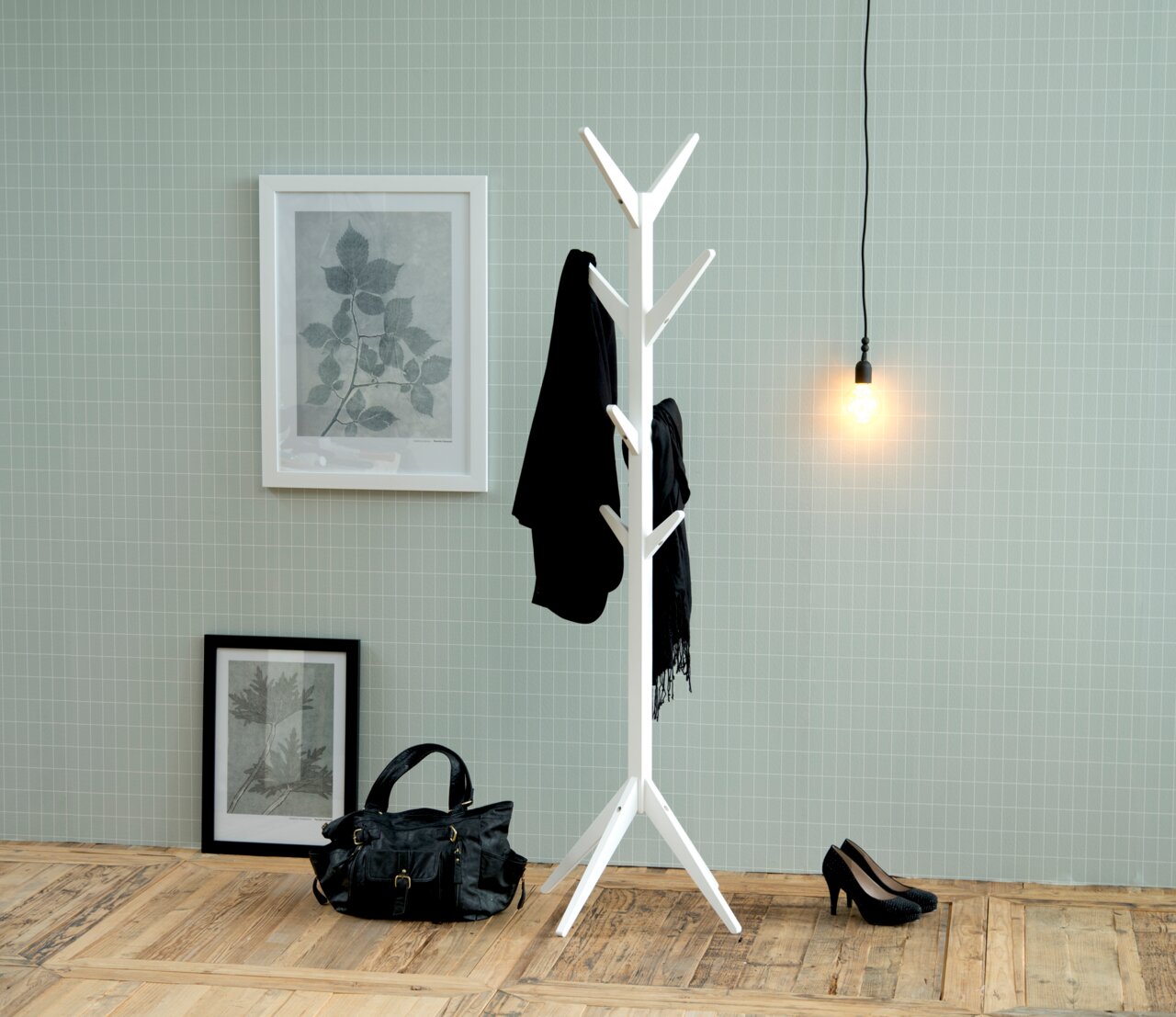 Weißer Garderobenständer mit mehreren Haken, frontal fotografiert, in einem stilvoll eingerichteten Raum mit Holzboden, Wandbildern und einer Hängelampe.