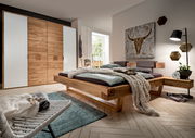 Moderner Kleiderschrank mit vier Türen in Holzoptik und weißen Elementen, seitliche Perspektive im stilvollen Schlafzimmer.