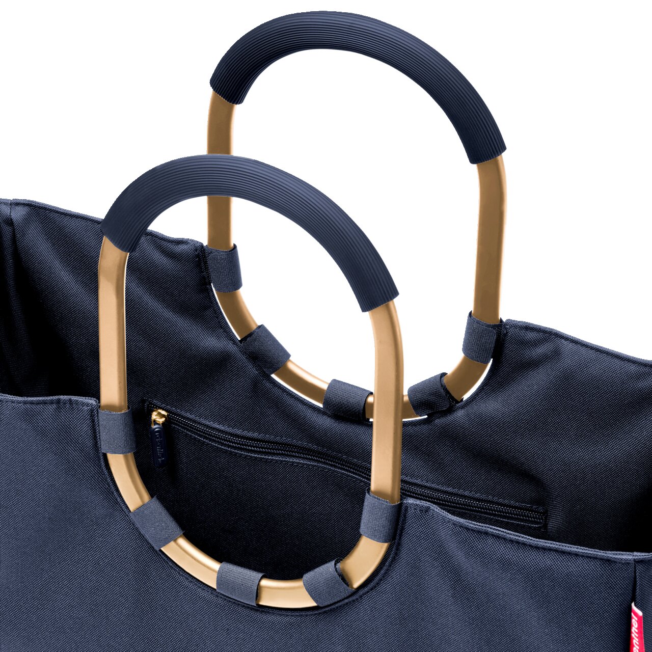 Nahaufnahme einer dunkelblauen Tasche mit goldenen, ovalen Griffen und Reißverschluss, perspektivisch von oben.