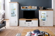 Wandmeubel in landhuisstijl in wit met eikenhouten look: vitrinekast, tv-lowboard en dressoir met glazen deuren en ledverlichting, van voren gefotografeerd vanaf ooghoogte in de woonkamer
