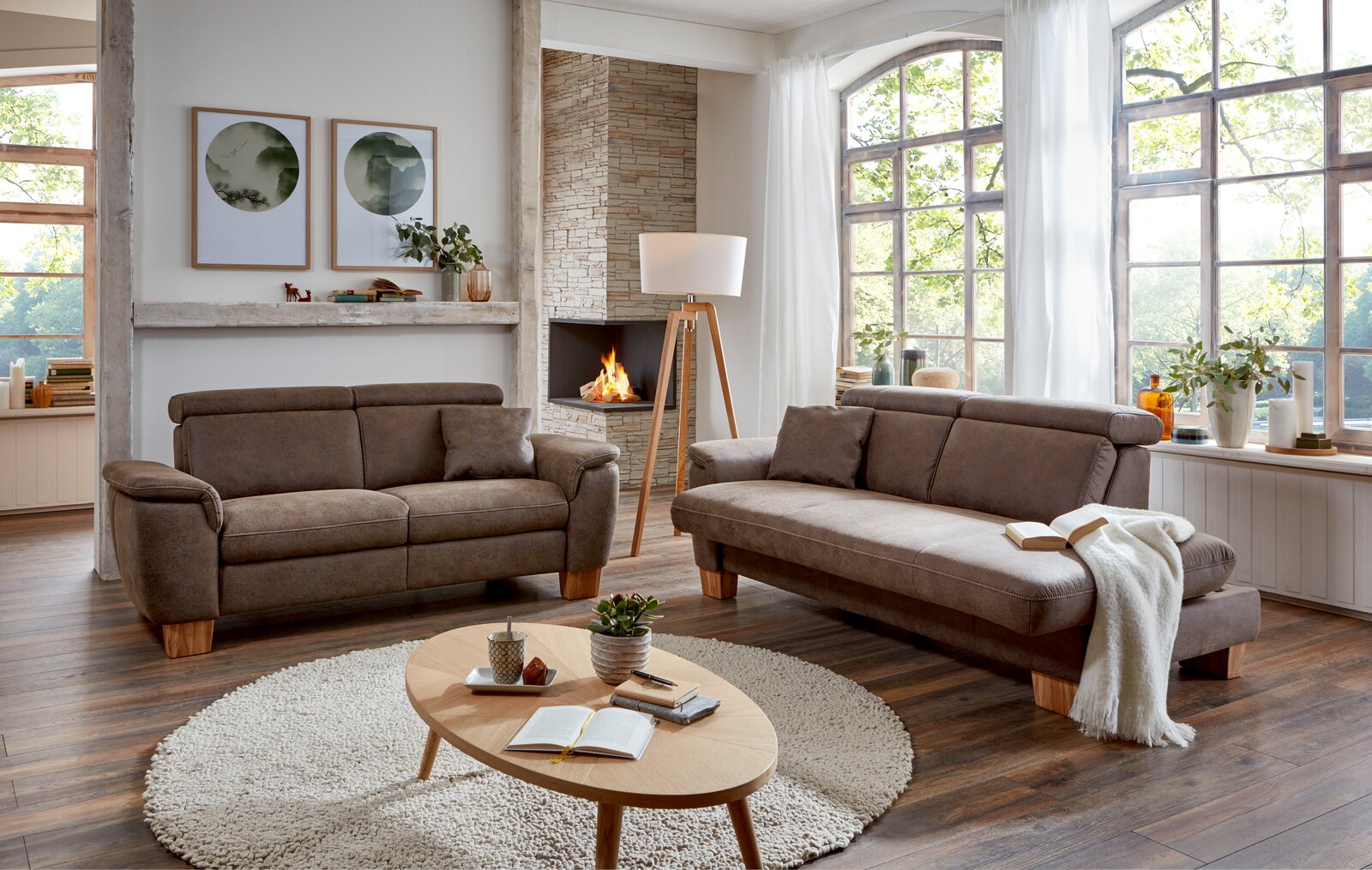 Gemütliches Wohnzimmer mit zwei braunen Sofas, einem runden Teppich und einem Holztisch, aus der Perspektive von vorne fotografiert.