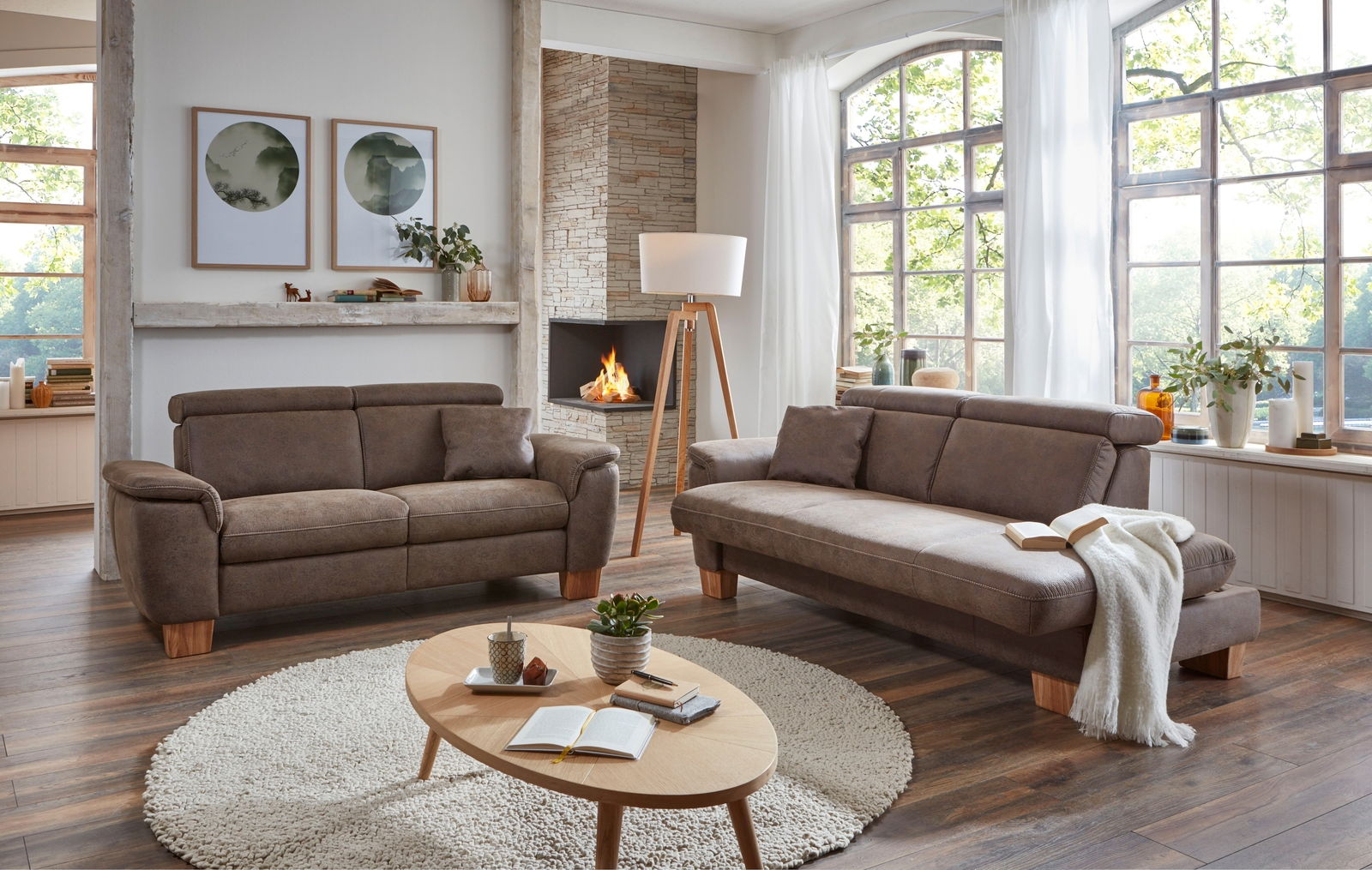 Gemütliches Wohnzimmer mit zwei braunen Sofas, einem runden Teppich und einem Holztisch, aus der Perspektive von vorne fotografiert.