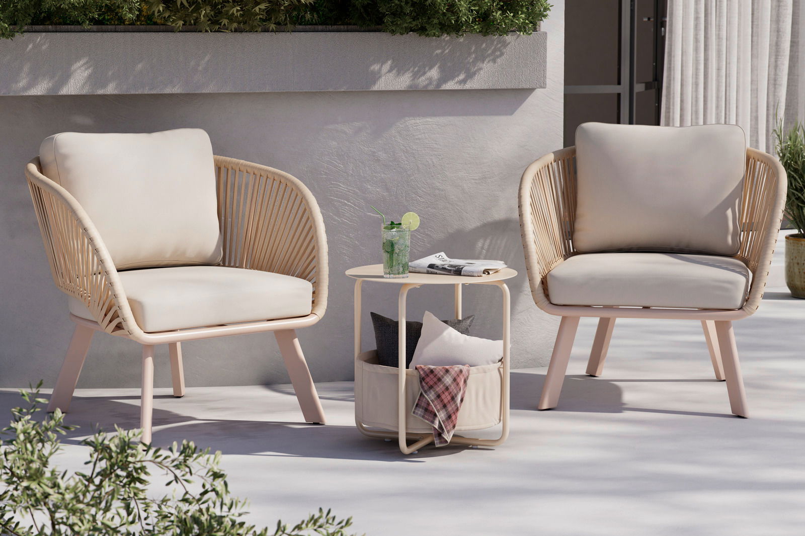 Ambia Garden Beistelltisch RUDI Beistelltisch aus hellem Holz mit runder Tischplatte, darunter ein Stoffkorb mit Kissen, im Freien zwischen zwei Sesseln, seitliche Perspektive
