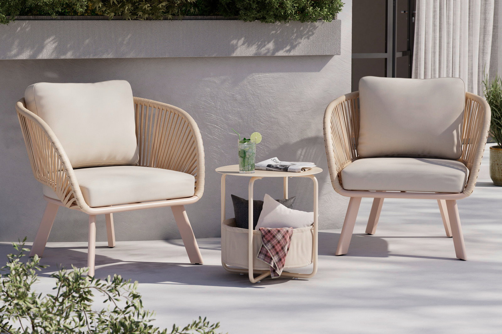 Ambia Garden Beistelltisch RUDI Beistelltisch aus hellem Holz mit runder Tischplatte, darunter ein Stoffkorb mit Kissen, im Freien zwischen zwei Sesseln, seitliche Perspektive