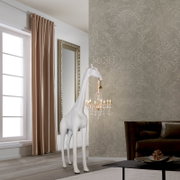 Weiße Giraffen-Standfigur als ausgefallene Stehlampe mit kleinem Kristall-Kronleuchter am Maul, in einem eleganten Wohnzimmer; Frontansicht in leichter Seitenperspektive