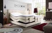 Boxspringbett in modernem Schlafzimmer, seitliche Perspektive, mit verstellbaren Matratzen und hellem Stoffbezug.
