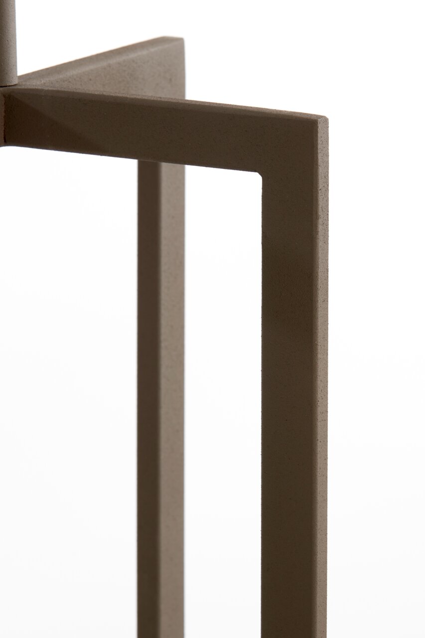 Close-up van een onderdeel van een staande lamp met een modern, geometrisch ontwerp in bruine kleur, gezien vanaf de zijkant.