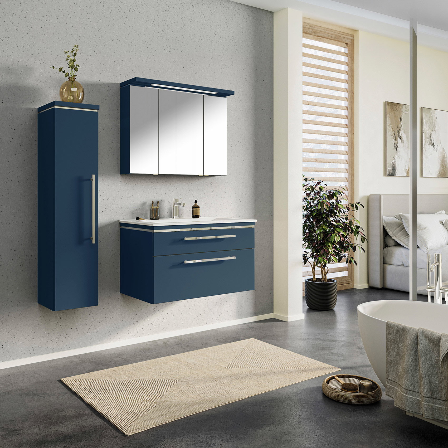 Modernes Badezimmer mit hängendem Badmöbel-Set in mattem Dunkelblau, weißem Waschtisch, dreitürigem Spiegelschrank mit LED-Beleuchtung und passendem Hochschrank vor heller Betonoptik-Wand.