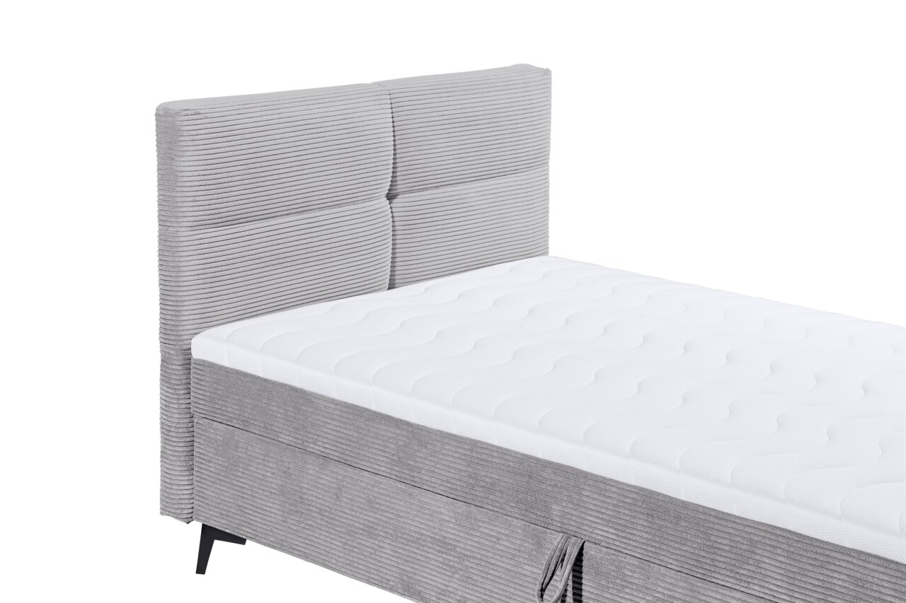 Graues Boxbett mit gestepptem Kopfteil und weißer Matratze, seitliche Perspektive