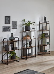 Drei offene Regale im Industrial-Design aus schwarzem Metall und Holz mit Deko, Pflanzen und Ordnern, frontale Perspektive im Wohnraum