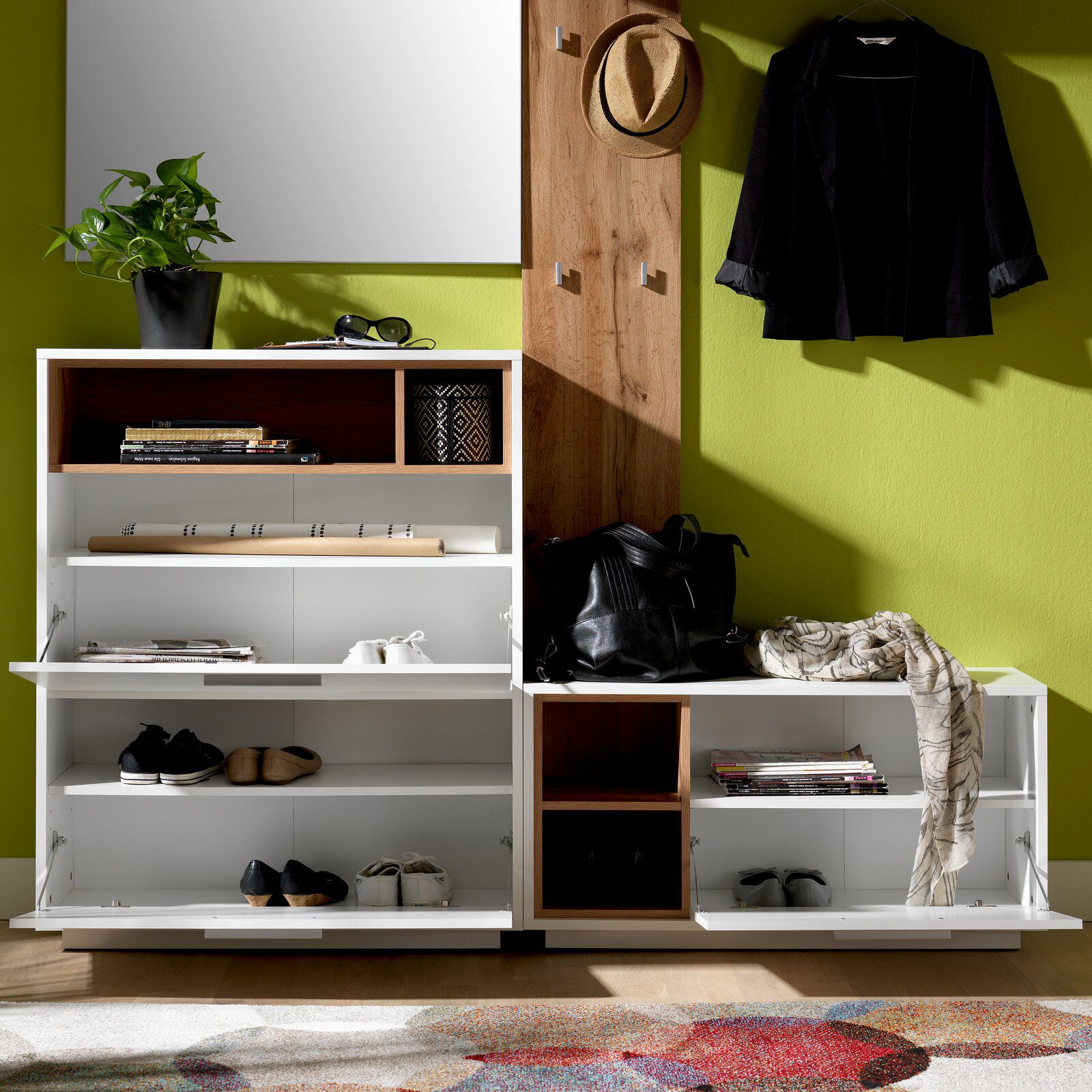 Kompakt-Garderobe mit Schuhregalen, Hakenleiste und Spiegel, frontal fotografiert. Enthält Dekorationen wie Pflanzen, Bücher und Kleidung.