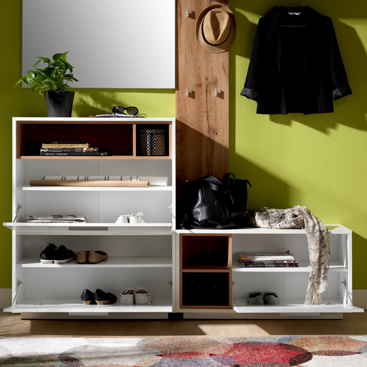 Kompakt-Garderobe mit Schuhregalen, Hakenleiste und Spiegel, frontal fotografiert. Enthält Dekorationen wie Pflanzen, Bücher und Kleidung.