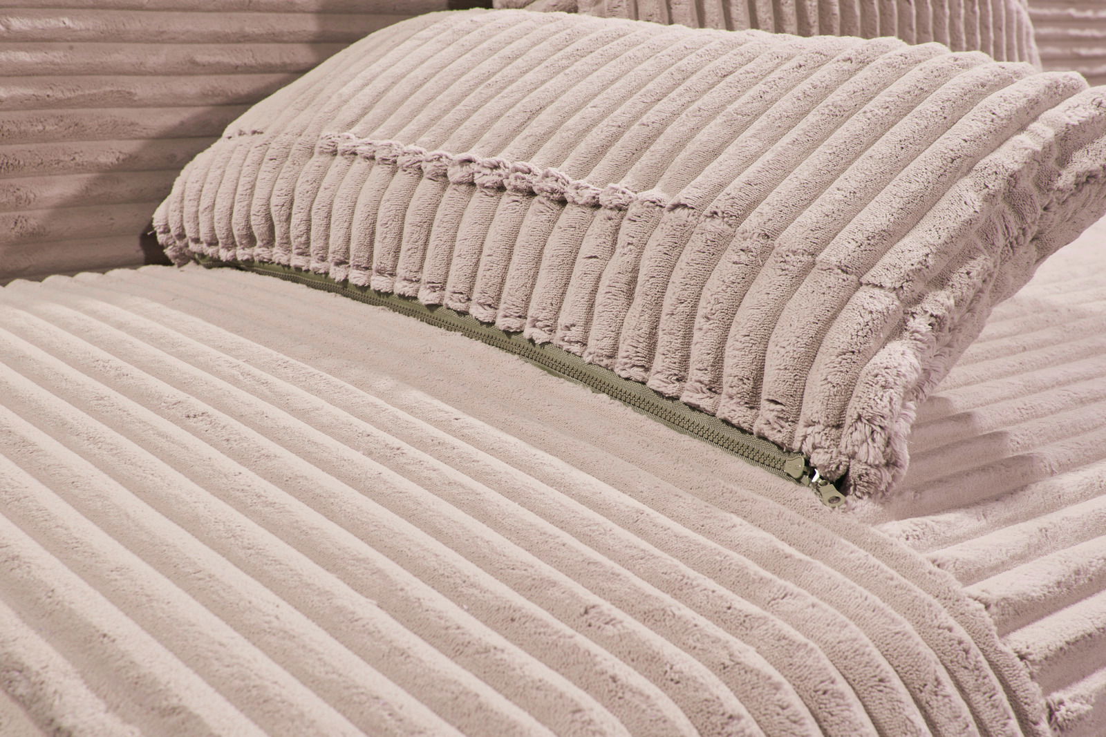 Nahaufnahme eines Funktionssofas mit weichem, geripptem Stoffbezug in Beige, Perspektive von der Seite.