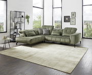 Grüne Eckgarnitur in modernem Wohnzimmer mit großen Fenstern, seitliche Perspektive