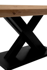 Nahaufnahme eines Esstisches mit einer Tischplatte aus Holz und einem schwarzen, gekreuzten Metallgestell.