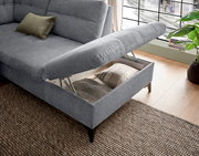 Graues Sofa mit hochgeklappter Sitzfläche, die Stauraum offenbart. Perspektive von schräg oben.