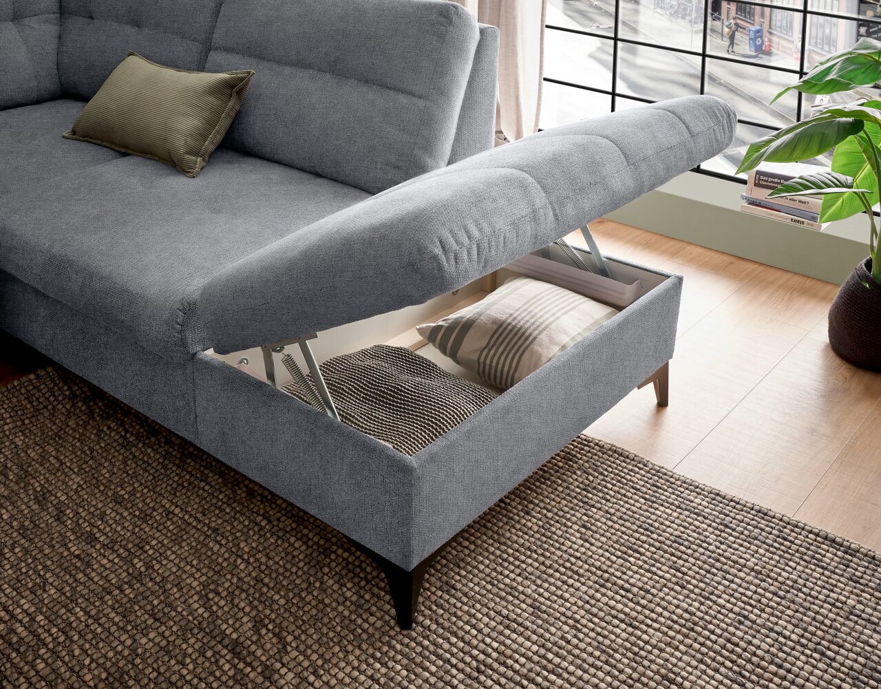 Graues Sofa mit hochgeklappter Sitzfläche, die Stauraum offenbart. Perspektive von schräg oben.