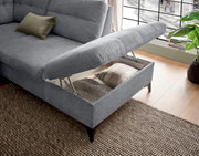 Graues Sofa mit hochgeklappter Sitzfläche, die Stauraum offenbart. Perspektive von schräg oben.