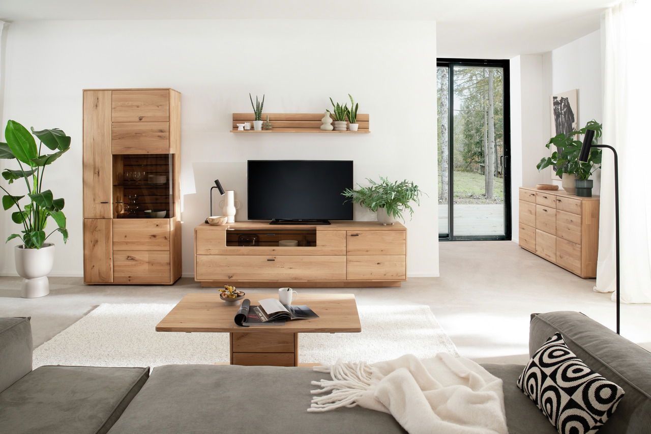 Wohnzimmer mit moderner Wandkombination aus Holz, bestehend aus einem hohen Schrank, einem TV-Board und einem Wandregal, frontal betrachtet.